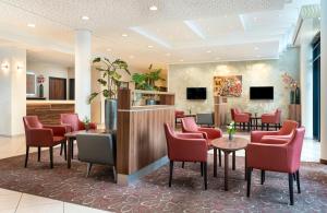 a waiting room with red chairs and tables at Leonardo Hotel Dresden Altstadt in Dresden