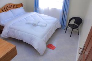 a bedroom with a white bed and a chair at Aurora Loisse Suites in Nakuru