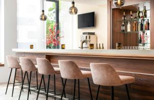 a bar with a row of stools in a room at Leonardo Hotel Dresden Altstadt in Dresden +28 photos