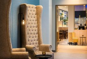 a living room with a chair and a table at Leonardo Hotel Hamburg Altona in Hamburg +49 photos