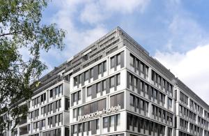 a tall white building with a sign on it at Leonardo Hotel Berlin Mitte in Berlin