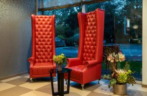 two red chairs and a table in a room at Leonardo Royal Hotel Köln - Am Stadtwald in Cologne +49 photos