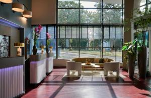 a living room with a couch and a table and windows at Leonardo Hotel Esslingen in Esslingen