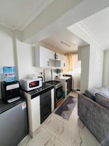 a kitchen with a stove top oven next to a couch at T-Homes in Thika +17 photos