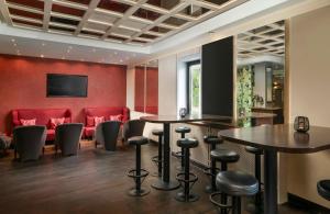 a bar with two tables and chairs and red chairs at Leonardo Hotel Mönchengladbach in Mönchengladbach