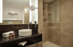 a bathroom with a sink and a shower at Leonardo Hotel Hamburg City Nord in Hamburg +36 photos