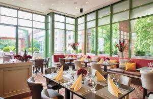 a restaurant with tables and chairs and large windows at Leonardo Hotel Mannheim City Center in Mannheim +36 photos