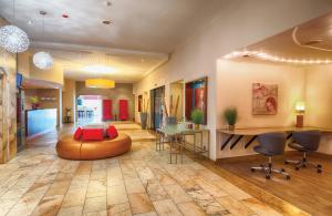 a lobby with a couch and a table and chairs at Leonardo Hotel Karlsruhe in Karlsruhe