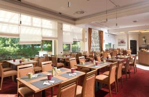 a dining room with tables and chairs and windows at Leonardo Hotel Karlsruhe in Karlsruhe