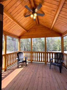a porch with two chairs and a ceiling fan at Cozy Coastal Cabin 2 in Steuben