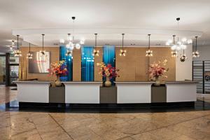a lobby with two reception desks with flowers at Leonardo Royal Hotel Frankfurt in Frankfurt