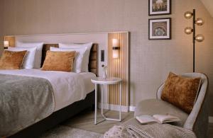 a bedroom with a bed and a chair and a table at Leonardo Royal Hotel Baden- Baden in Baden-Baden