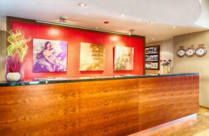 a bar in a restaurant with paintings on the wall at Leonardo Hotel Karlsruhe in Karlsruhe