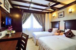 a hotel room with two beds and a desk and a television at Hotel Kooler Inn in Kota Kinabalu