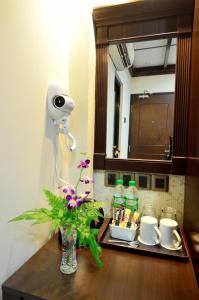- une salle de bains avec un vase de fleurs sur une table dans l'établissement Hotel Kooler Inn, à Kota Kinabalu