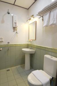 a bathroom with a toilet and a sink and a mirror at Hotel Kooler Inn in Kota Kinabalu