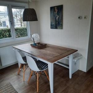a dining room table with two chairs and a lamp at Zeeotter AanZee in Biggekerke