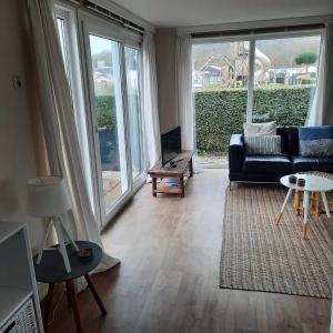 a living room with a couch and a large window at Zeeotter AanZee in Biggekerke