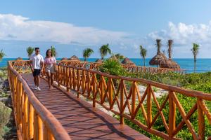 a man and a woman walking on a wooden bridge at Ocean Allure Costa Mujeres - Adults Only - All Inclusive in Costa Mujeres