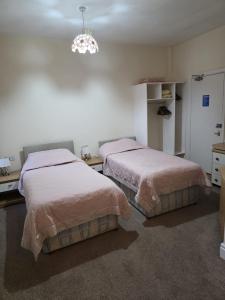a bedroom with two beds and a chandelier at The Ormerod in Burnley