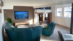 a living room with two blue chairs and a tv at Chez Netty Gite avec sauna à Beblenheim in Beblenheim