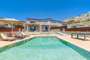 a swimming pool in front of a house at Villa Chloe Seastone by Villa Plus in Kiotari