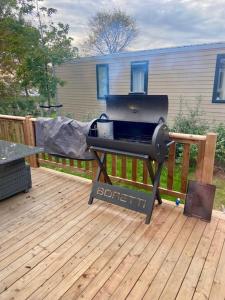 a grill on a wooden deck with a fence at Chalet Levy in Lauwersoog