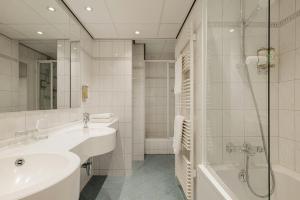 a bathroom with a sink and a shower and a tub at Leonardo Hotel Den Haag Babylon in The Hague
