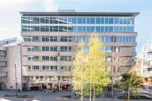 an office building with a tree in front of it at Leonardo Hotel Eindhoven City Center in Eindhoven