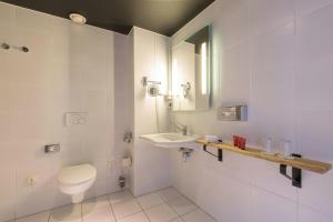 a bathroom with a toilet and a sink and a mirror at Leonardo Hotel Almere City Center in Almere