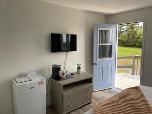 a bedroom with a refrigerator and a television on the wall at Buoy & Arrow Suites in Rocky Harbour