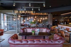 a restaurant with red leather couches and a table at Leonardo Hotel Papendrecht in Papendrecht