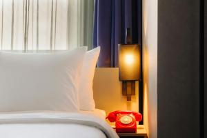 a bed with a white pillow and a red alarm clock at Leonardo Hotel Amsterdam Leidse Square in Amsterdam