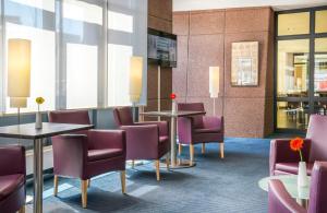 a waiting room with purple chairs and tables at Hotel Freiburg City Center by Leonardo Hotels in Freiburg im Breisgau