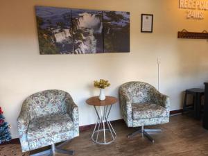 two chairs in a room with a table and a painting at Terra Iguazú Suites in Puerto Iguazú +37 photos