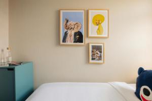 a bedroom with four pictures on a wall at Leonardo Hotel Amsterdam Leidse Square in Amsterdam
