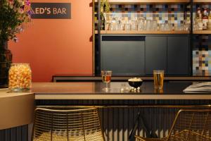 a bar with two glasses of beer on a counter at Leonardo Hotel Amsterdam Leidse Square in Amsterdam
