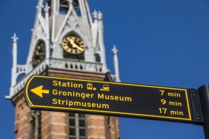 a street sign with a clock tower in the background at Leonardo Hotel Groningen Stadspark in Groningen +88 photos