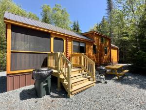 a log cabin with a staircase and a grill at Cozy Coastal Cabin 3 in Steuben