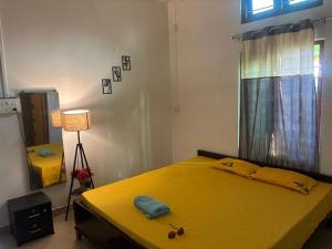 a bedroom with a yellow bed and a window at Debox heaven Homestay in Jorhat