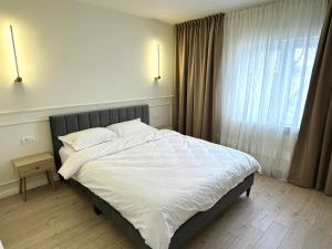 a bedroom with a bed with white sheets and a window at Max Apartment in Ocna-Mureşului