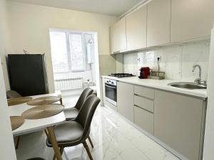 a kitchen with white cabinets and a table and chairs at Max Apartment in Ocna-Mureşului