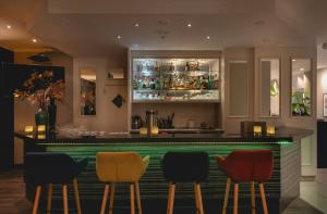 a bar in a restaurant with colorful stools at Leonardo Hotel Heidelberg City Center in Heidelberg