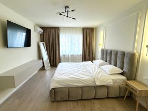 a bedroom with a large bed and a flat screen tv at Max Apartment in Ocna-Mureşului +2 photos