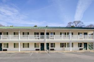 an old white building with a balcony and a parking lot at Plantation Inn & Suites Near Locust Grove I 75 in Jackson