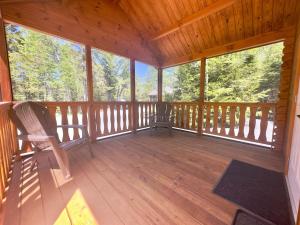 a cabin with a rocking chair on a wooden porch at Cozy Coastal Cabin 4 in Steuben