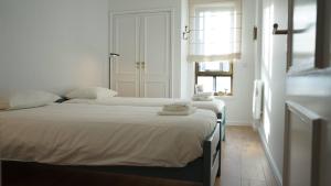 a white bedroom with two beds and a window at Porto Plage de Matosinhos in Matosinhos