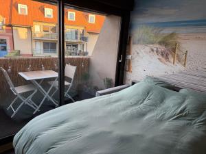 a bedroom with a bed and a table on a balcony at L'effet Dune in Sangatte