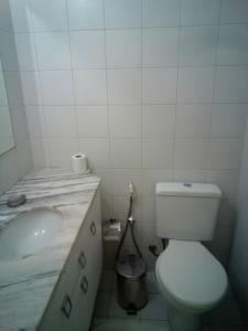 a white bathroom with a toilet and a sink at Apartamento Enseada Praia do Forte in Praia do Forte