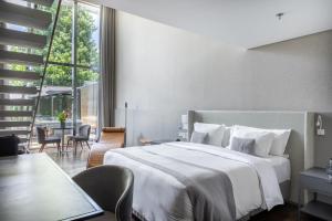 a bedroom with a large white bed and a table at Suryaa Hotel Pinhais, Curio Collection by Hilton in Pinhais